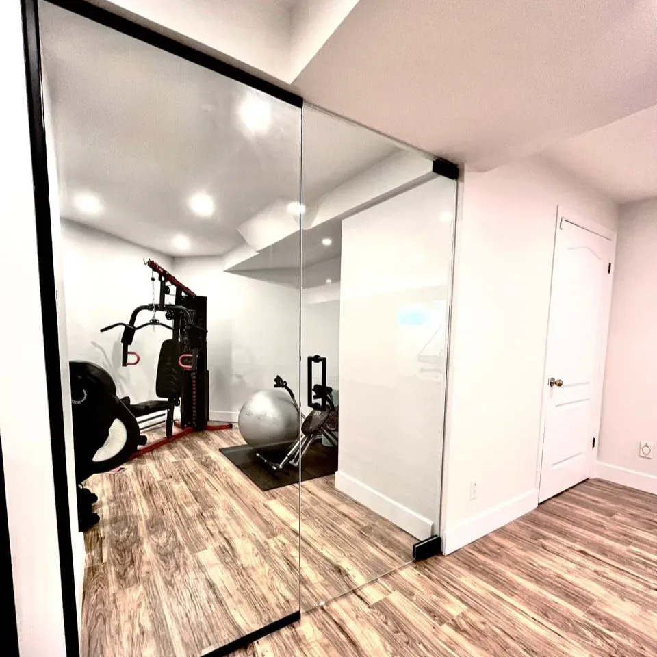 Home gym behind a frameless glass wall in a finished basement