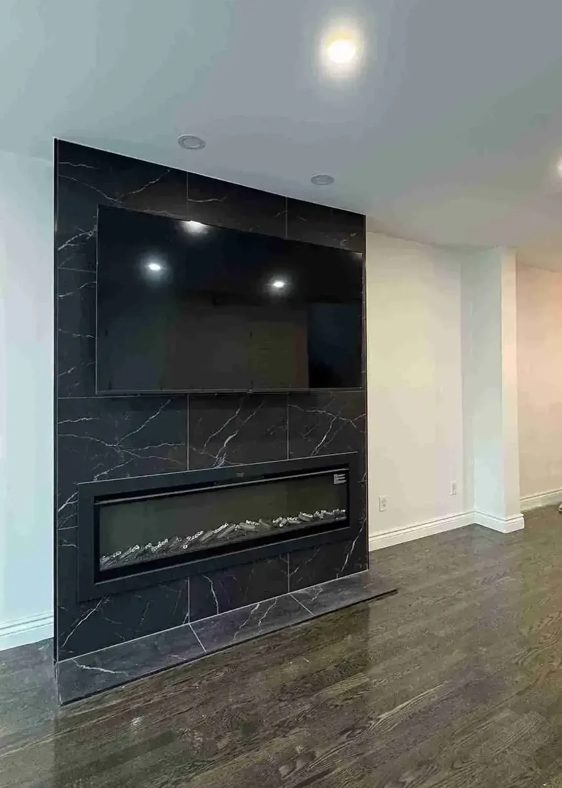 Media wall with linear electric fireplace in black marble-look tile