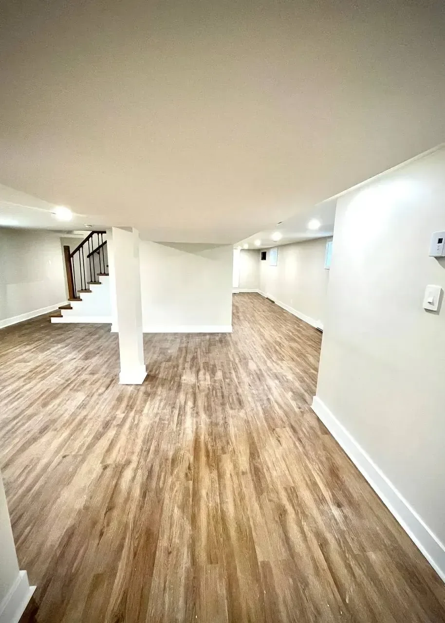 Open finished basement with new stairs and vinyl plank flooring
