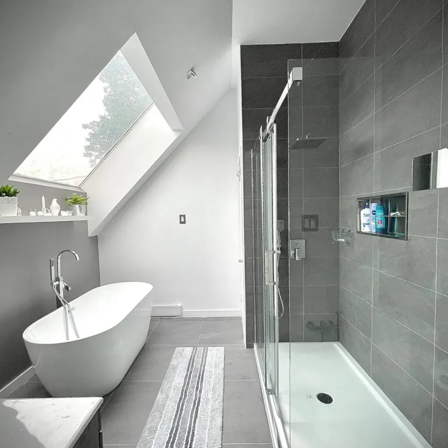 Attic bathroom with skylight, freestanding tub, and glass shower