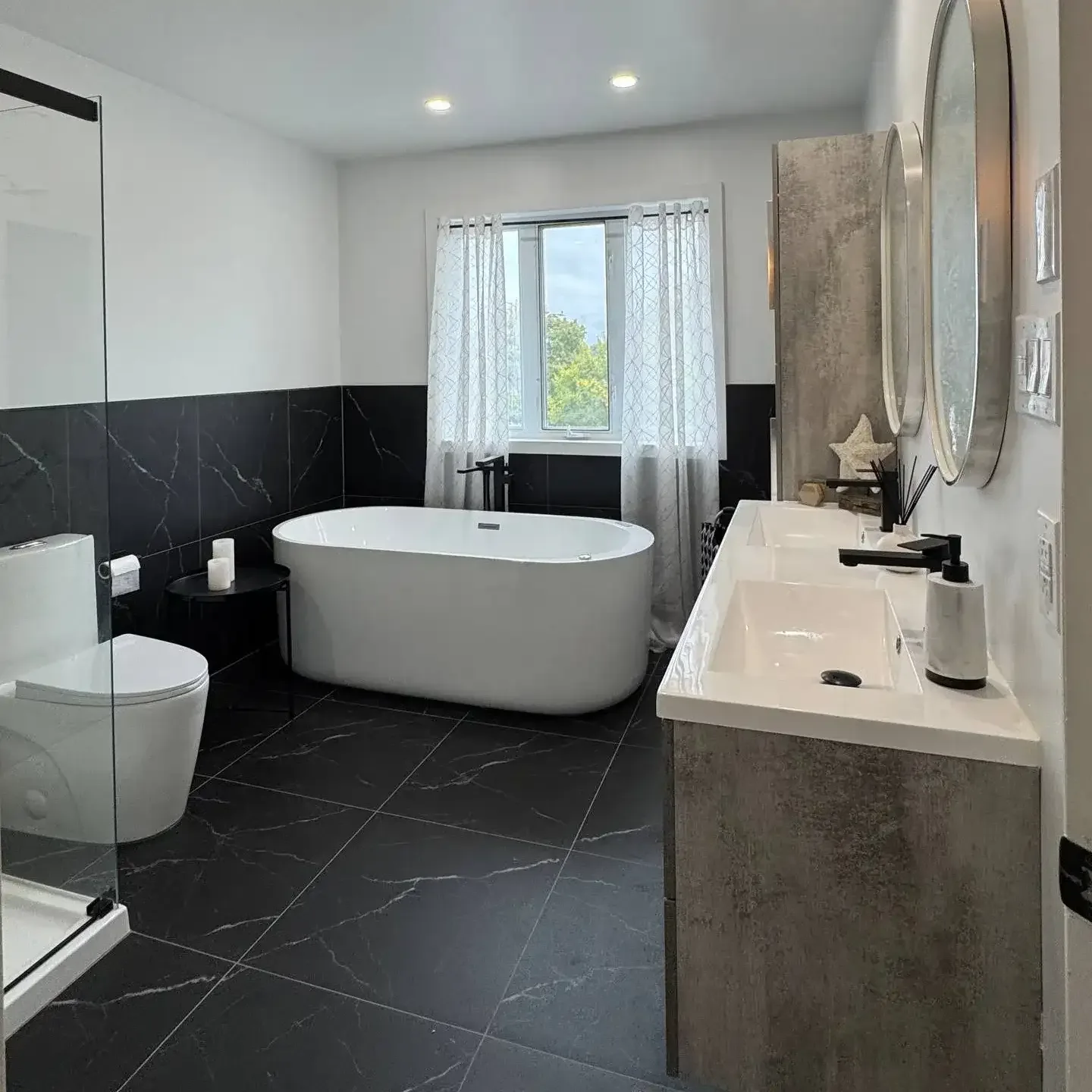Bathroom with black marble-look wainscot tile and freestanding tub
