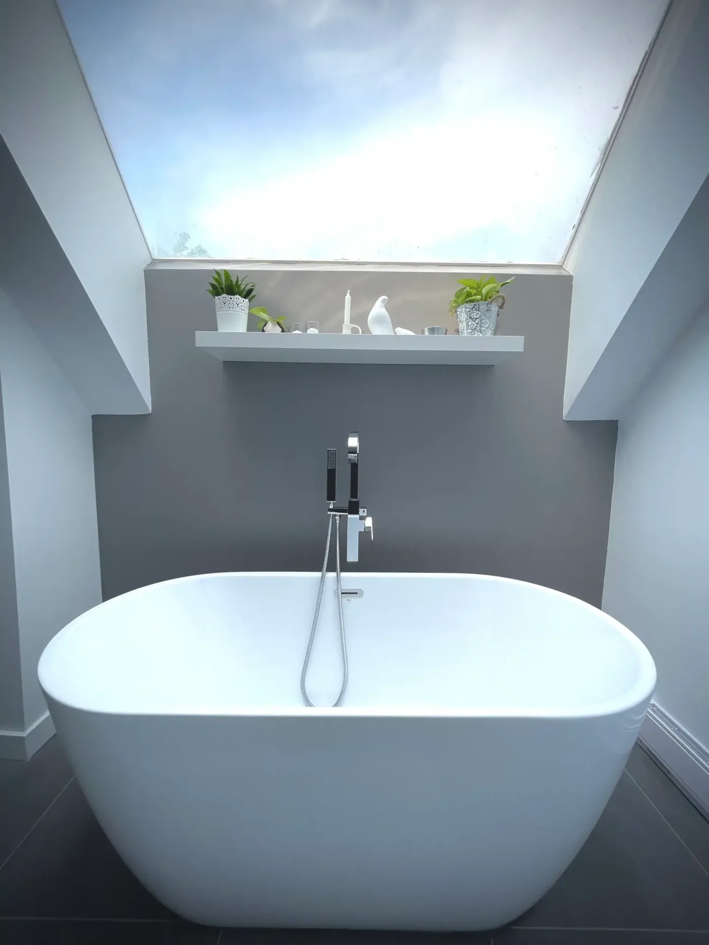 Freestanding tub under a skylight with wall-mounted hand shower