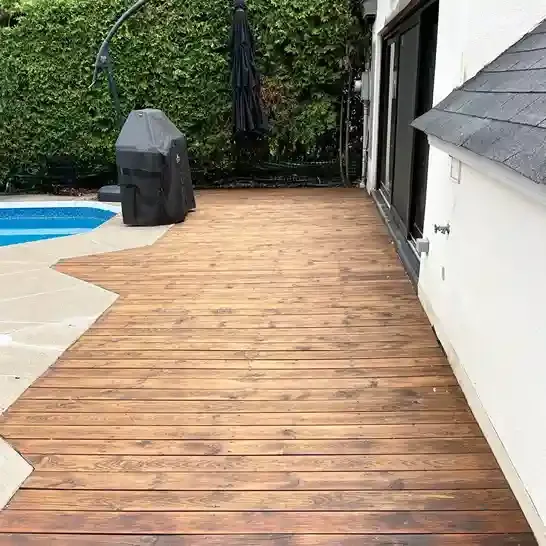 New wood deck installed beside a backyard pool