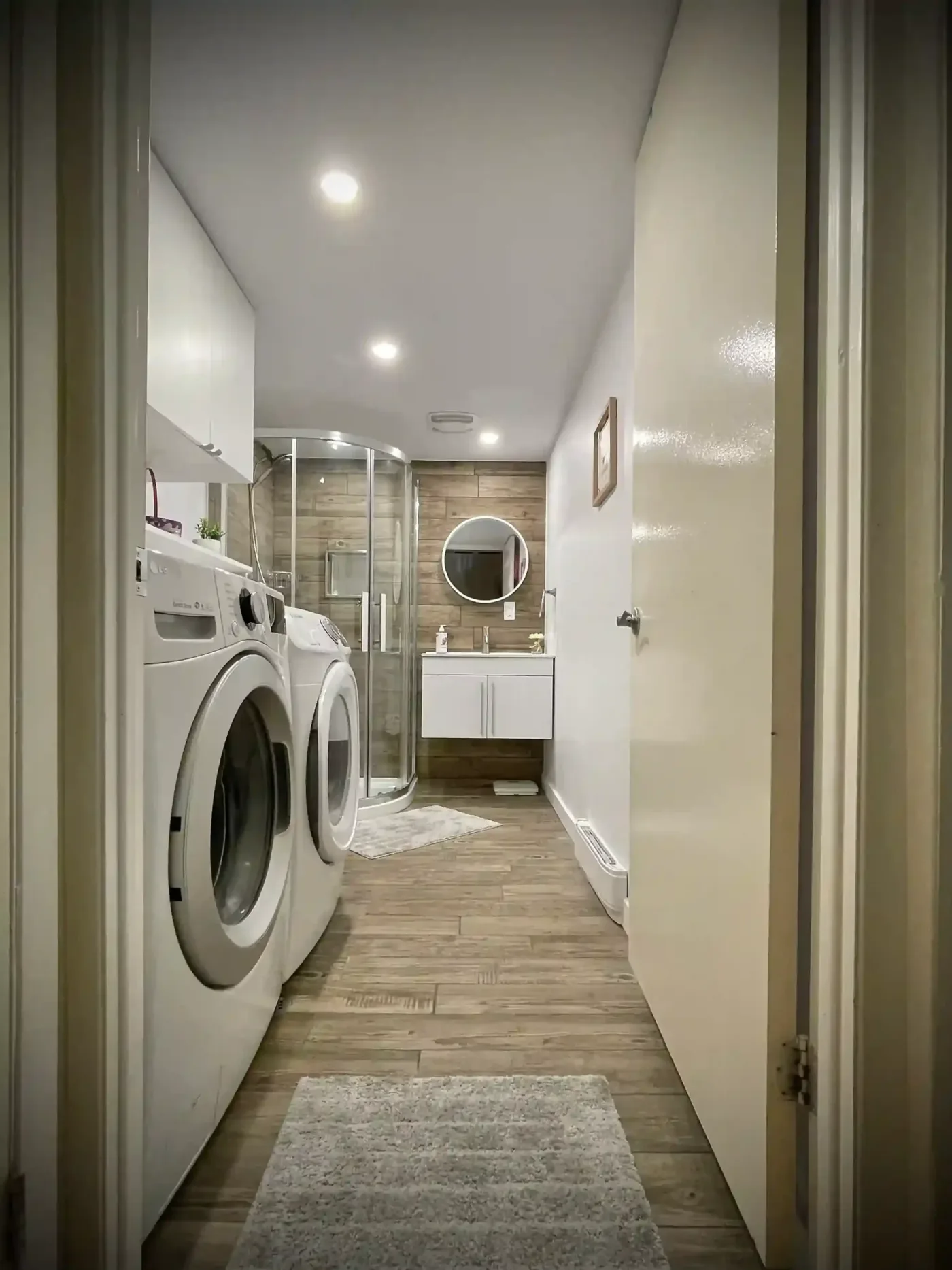Combined laundry and bathroom with wood-look tile and corner shower