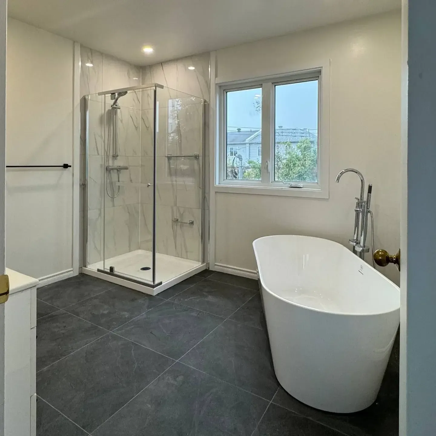 Renovated bathroom with dark slate tile and freestanding tub