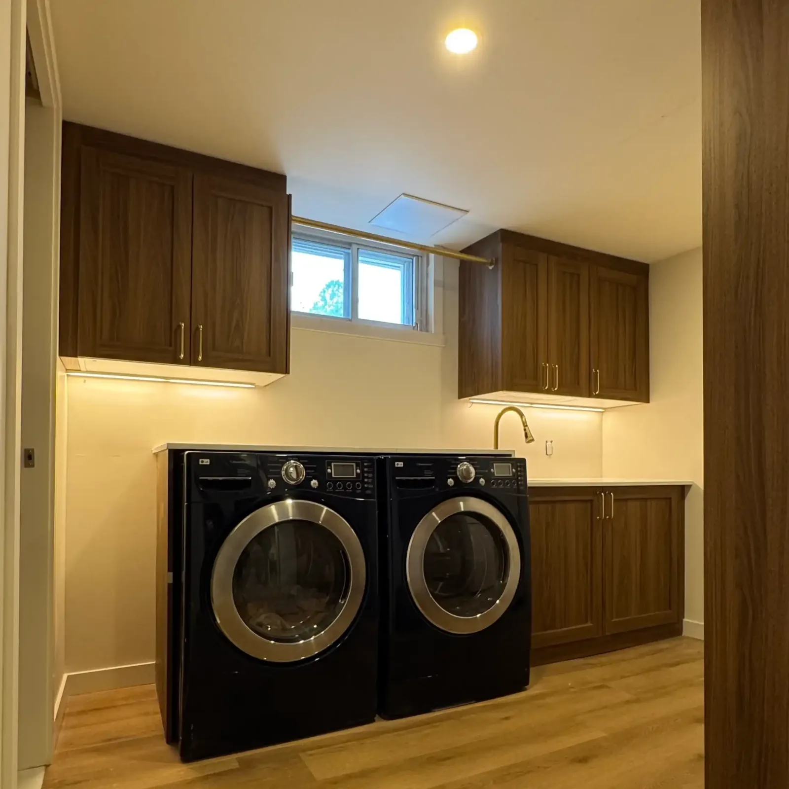 Rebuilt laundry room with walnut cabinetry and under-cabinet lighting