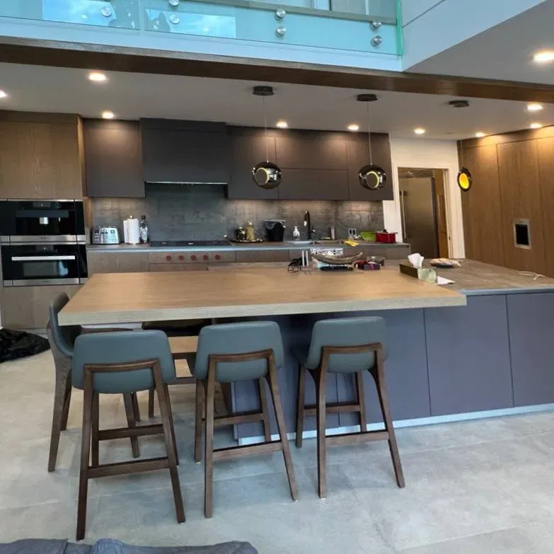 Open kitchen with oak island top below a glass mezzanine
