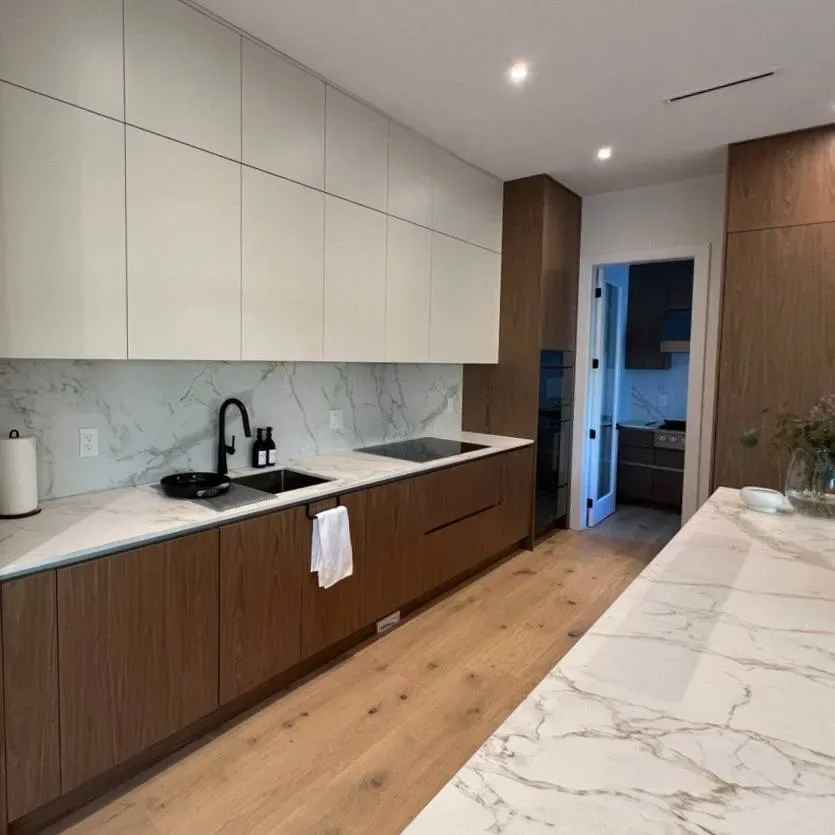 Kitchen with walnut lower cabinets, white uppers, and marble-look backsplash
