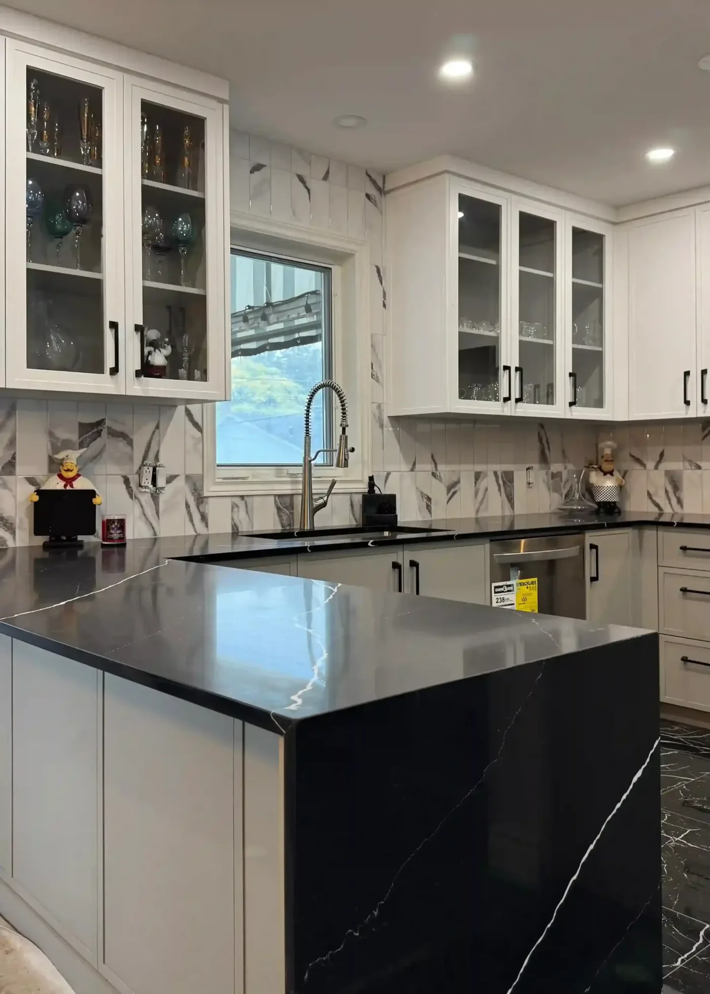 White kitchen with glass-front uppers and black quartz counters